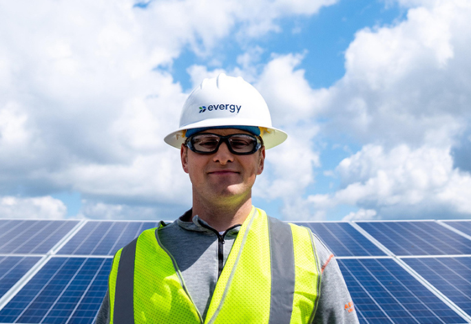 An Evergy employee stands in front of solar panels